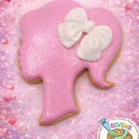 Pink Barbie silhouette iced cookie with white bow on sparkly pink background